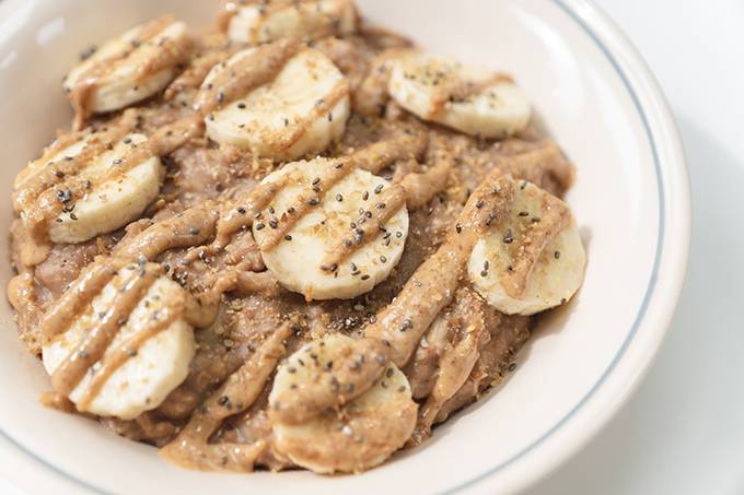 Close up of a white bowl of peanut butter and chocolate banana porridge