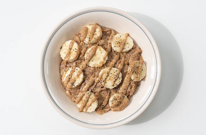 The view from above of a white bowl containing peanut butter and chocolate banana porridge