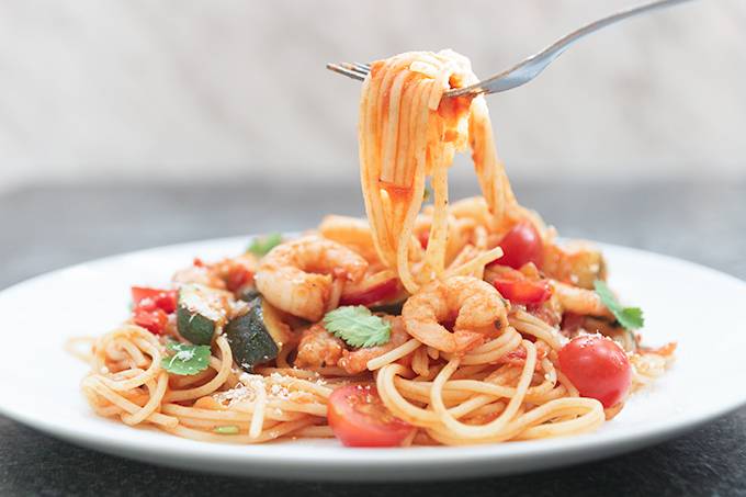 A plate of prawn, chilli and tomato spaghetti with a fork digging in