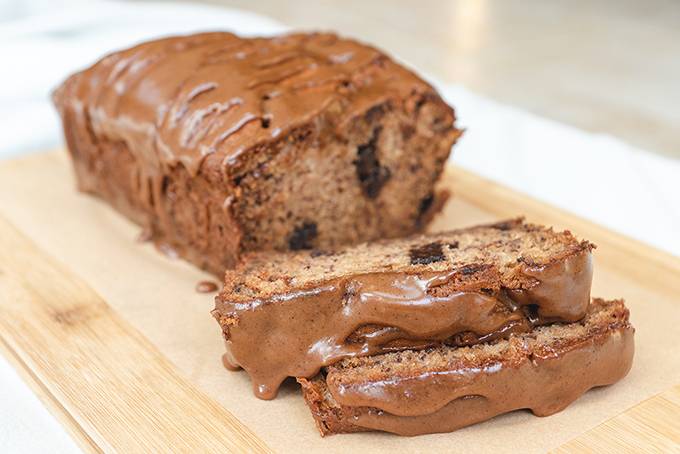 Biscoff and chocolate chip banana bread on a wooden board, with two slices cut