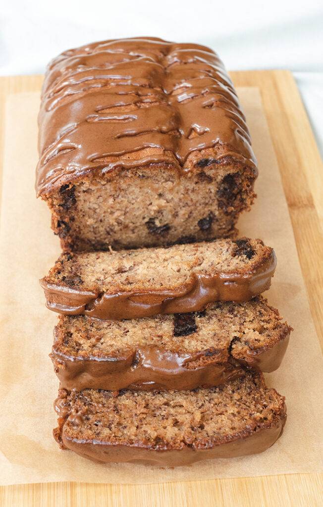 Biscoff and chocolate chip banana bread on a wooden board, with three slices cut