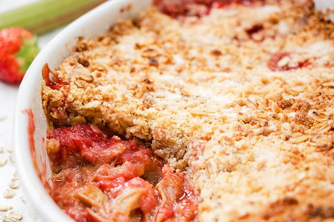 Close up view of a strawberry and rhubarb crumble in a white baking dish