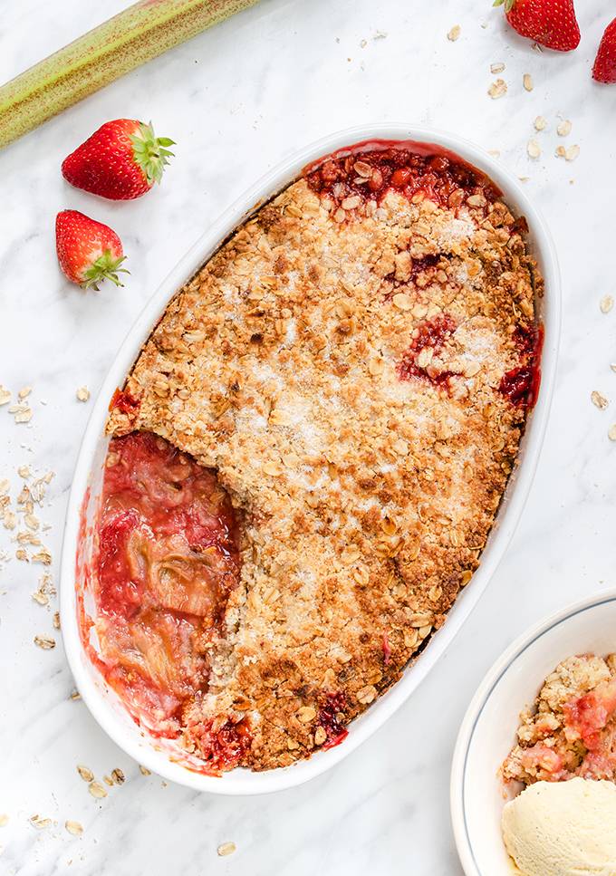 Top down view of a strawberry and rhubarb crumble in a white baking dish