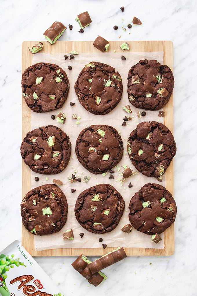 Top down view of a board containing  nine aero mint chocolate chip cookies.