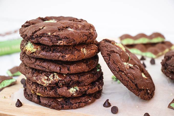 A stack of aero mint chocolate chip cookies with another cookie leaning against it.