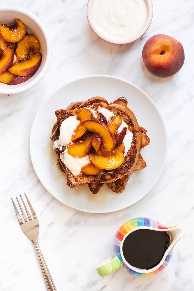 Top down view of a plate of French toast topped with caramelised peaches and yoghurt