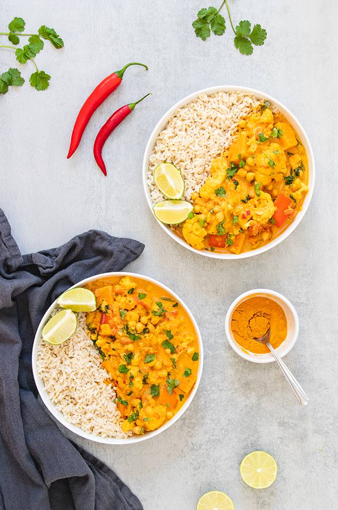 Top down view of two bowls of cauliflower and chickpea curry and rice