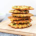 A stack of fried vegetable fritters on a wooden board.
