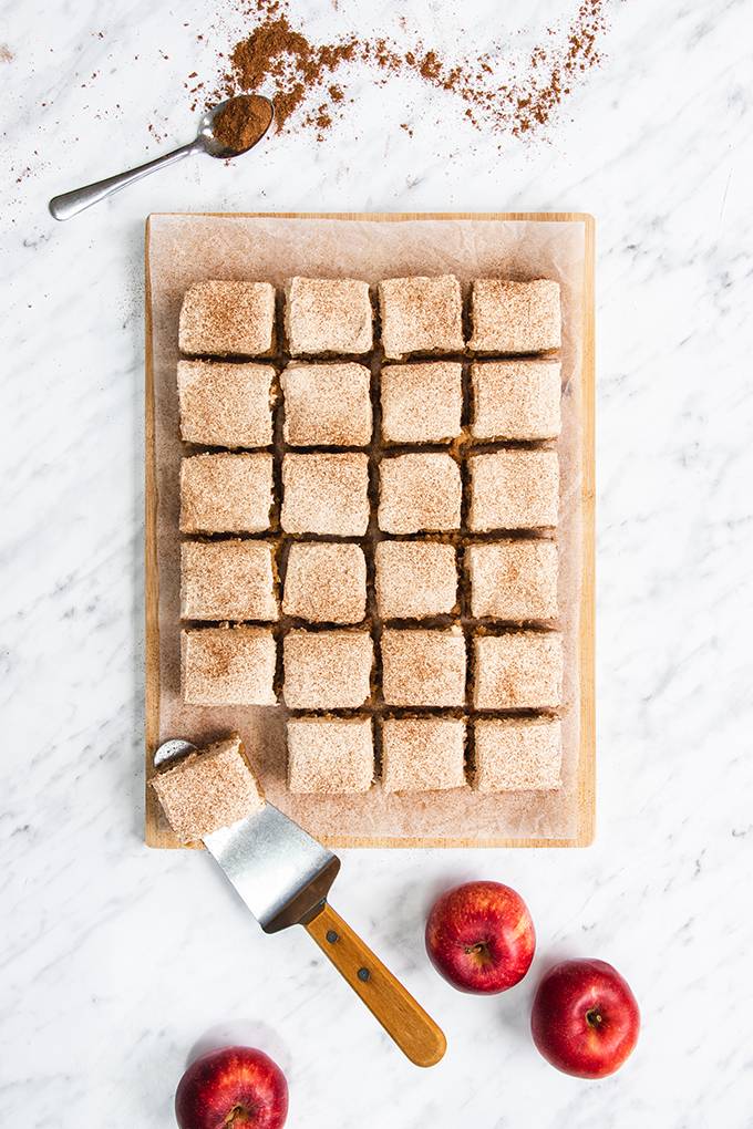 Top down view of 24 squares of apple and cinnamon cake on a wooden board.