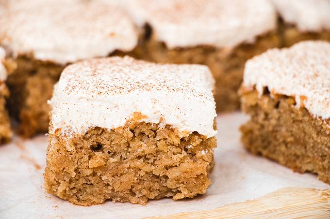 Close up of a square of apple and cinnamon cake with icing on top.