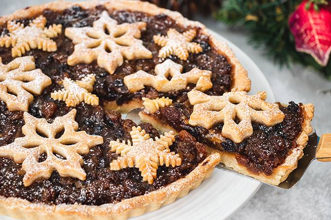 Close up of a Christmas mincemeat tart, with one slice being taken of it.