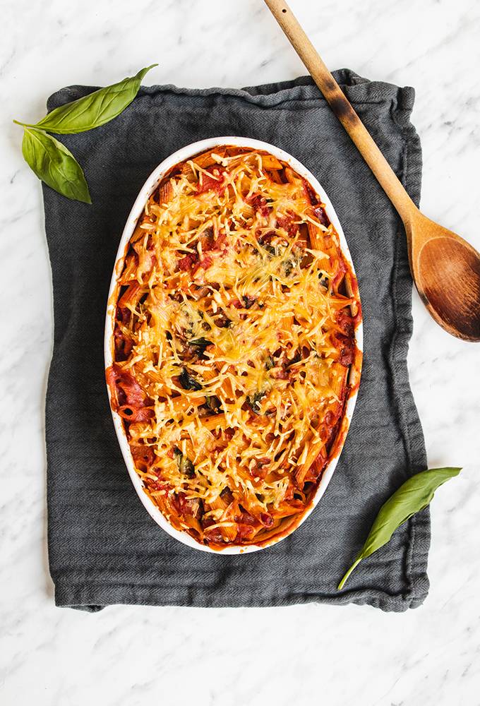 Top down view of a cheese and tomato pasta bake in a white oven dish