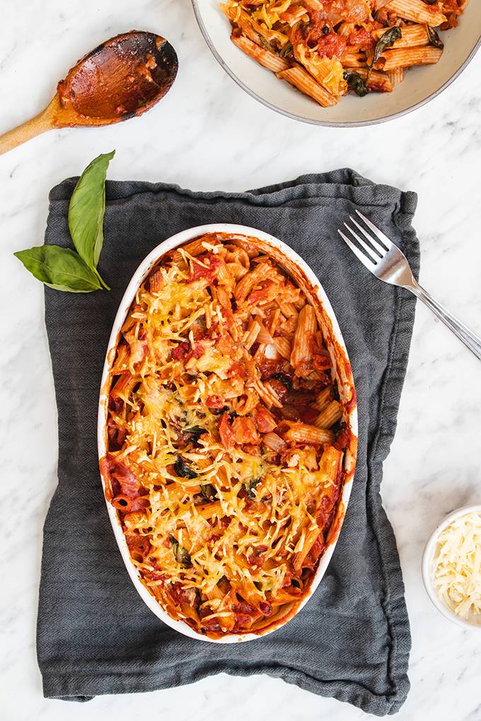 Top down view of a cheese and tomato pasta bake in a white oven dish