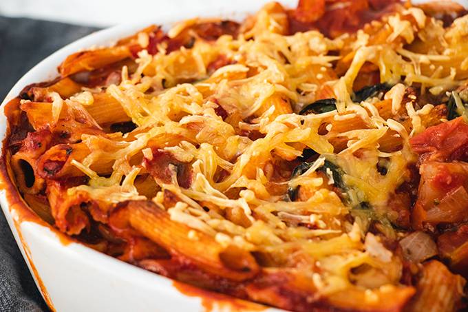 Close up of a dairy free pasta bake in a white oven dish, with crispy cheese on the top