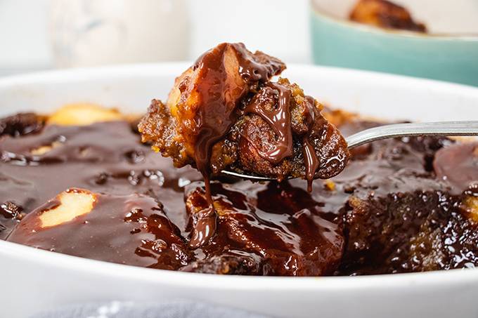 Close up of a spoonful of pear and ginger pudding, drizzled with chocolate sauce.