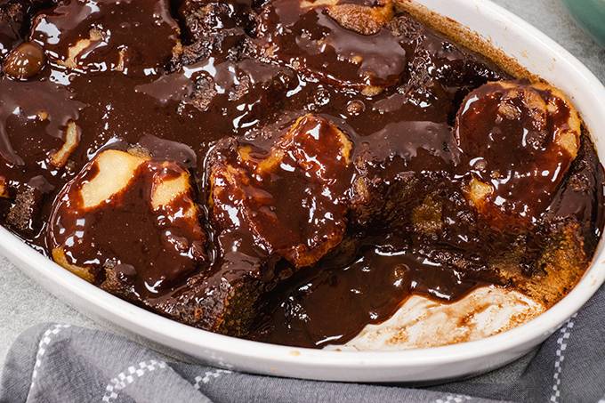 Pear and ginger pudding in a white dish, with chocolate sauce drizzled over the top.