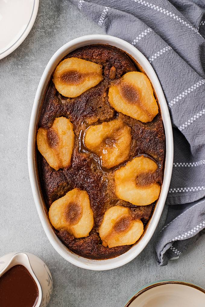 Top down view of a pear and ginger pudding in a white dish.