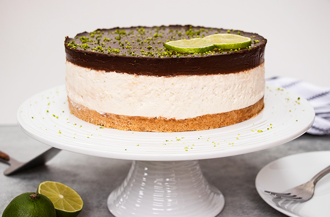 A chocolate and lime cheesecake on a white cake stand.