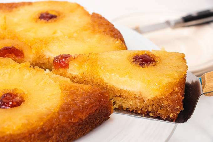 Close up of a slice being taken out of a gluten and dairy free pineapple upside down cake.