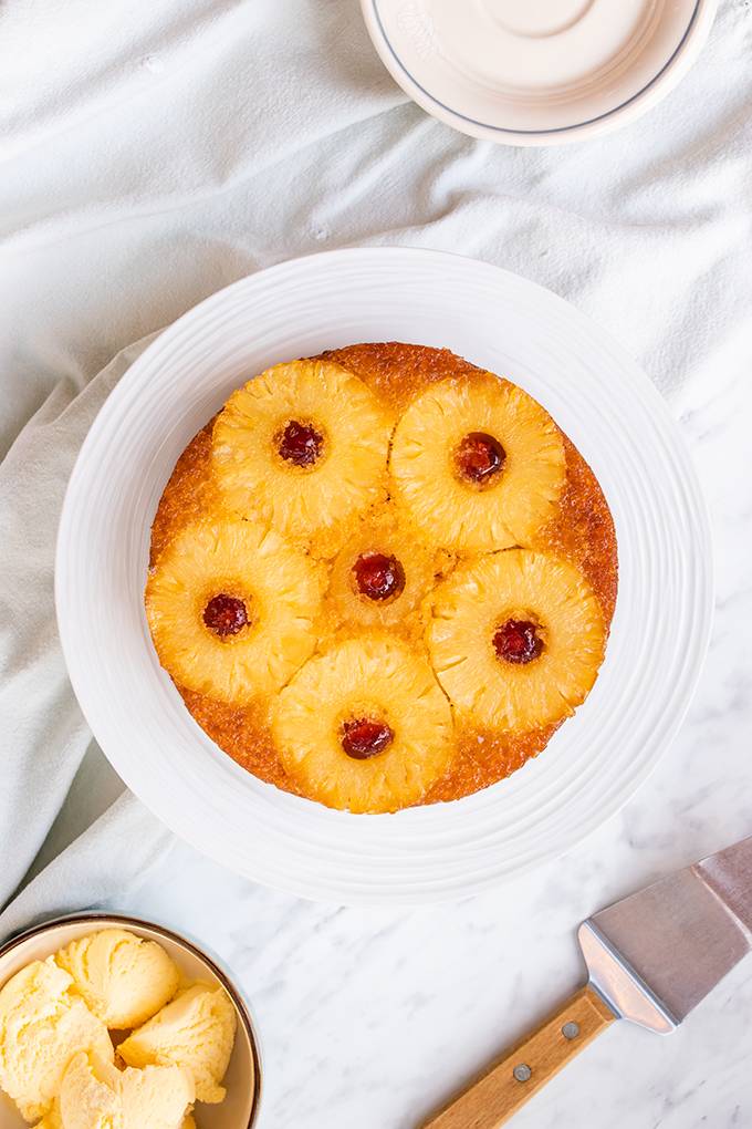Top down view of a pineapple upside down cake on a white plate.
