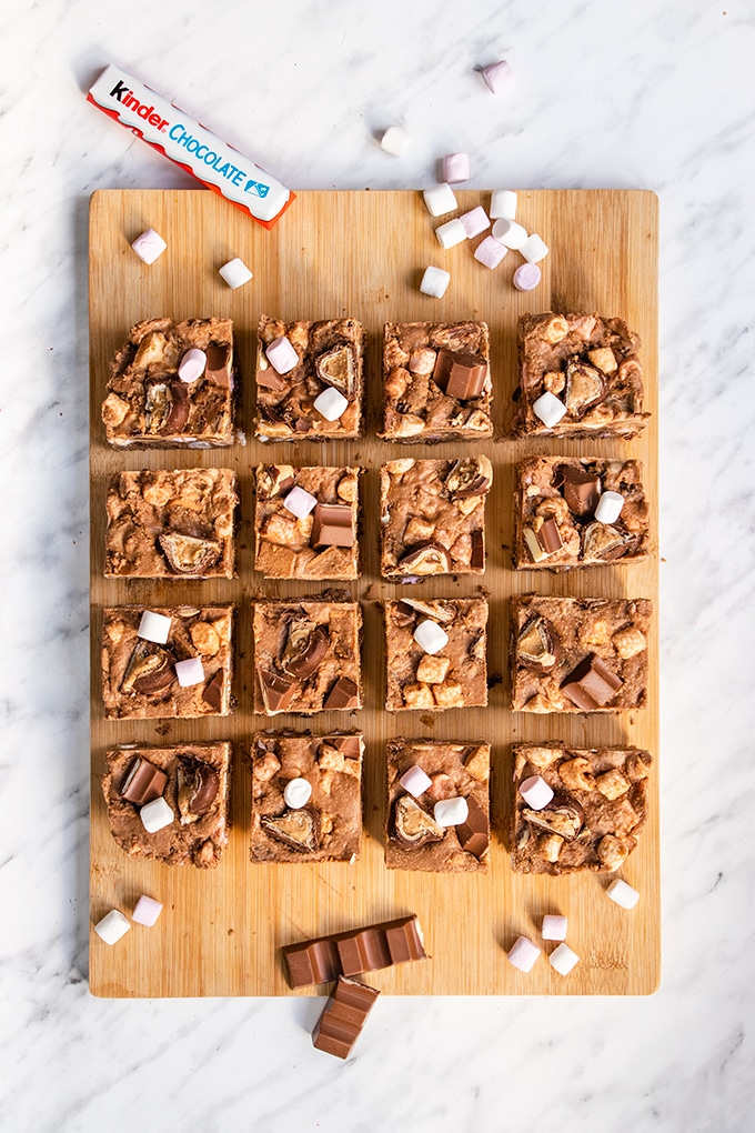 Top down view of 16 squares of Kinder rocky road on a wooden board.