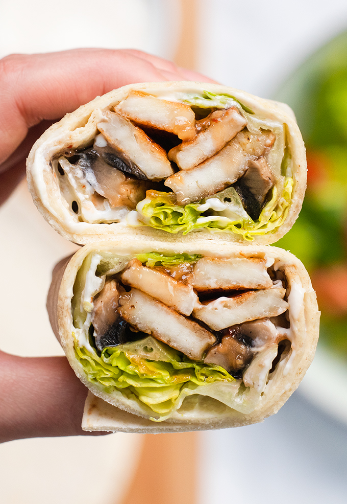 Close up of a mushroom and halloumi wrap that has been cut in half.