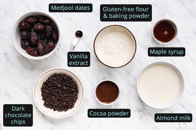 Top down view of all ingredients required to make vegan date brownies, laid out in bowls.