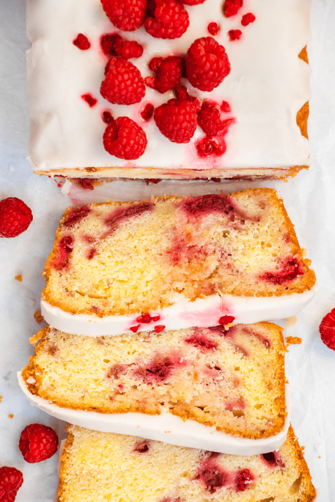 Top down view of a lemon and raspberry drizzle cake that's been cut into slices.