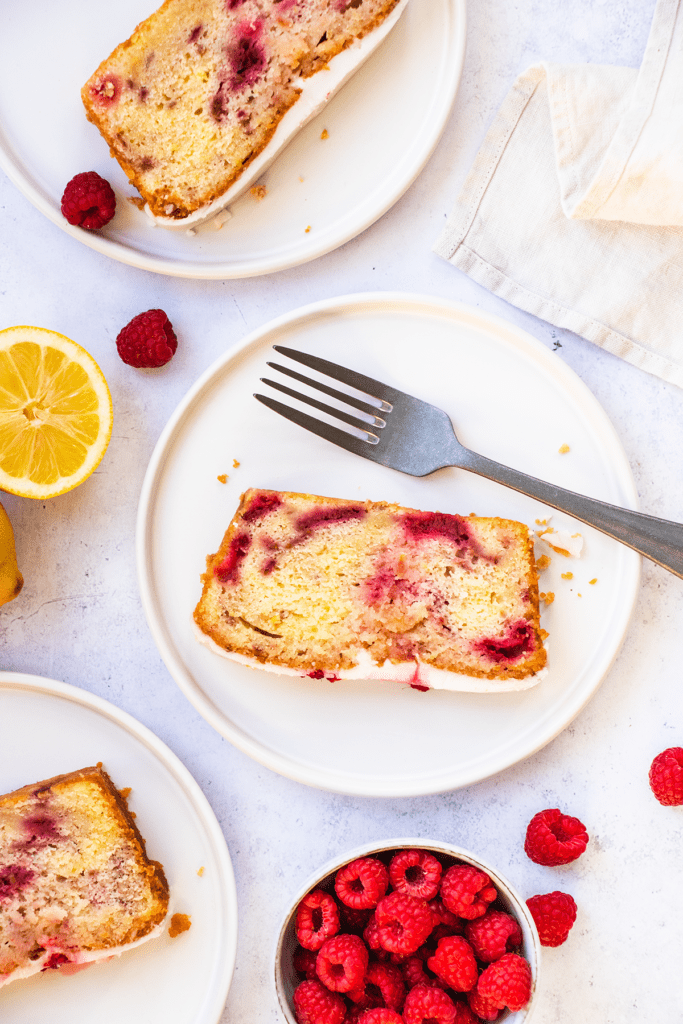 Top down view of slices of lemon and raspberry cake on individual plates.