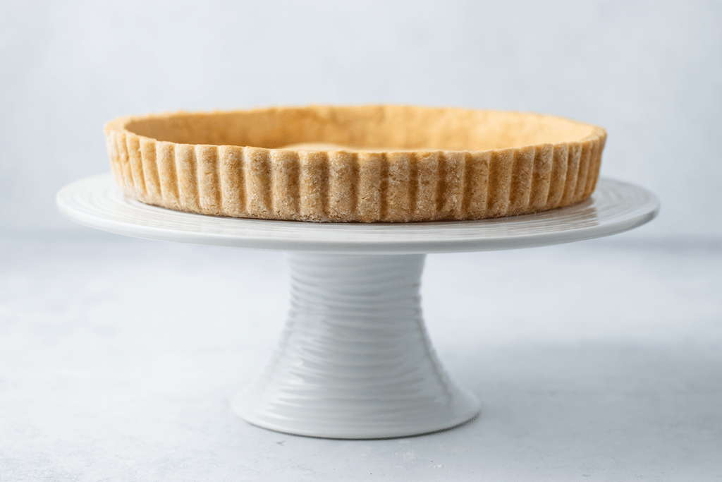 A gluten free tart crust on a white cake stand