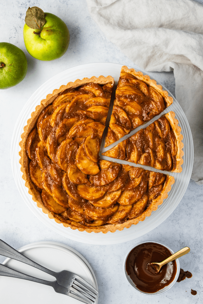 Top down view of a sliced toffee apple tart on a cake stand