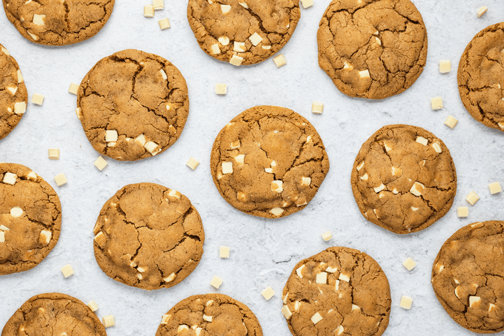 Top down view of white chocolate and ginger cookies with white chocolate chips scattered around