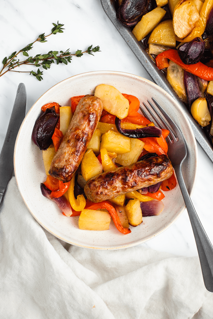 Sausage and veg tray bake served in a dish with a knife and fork