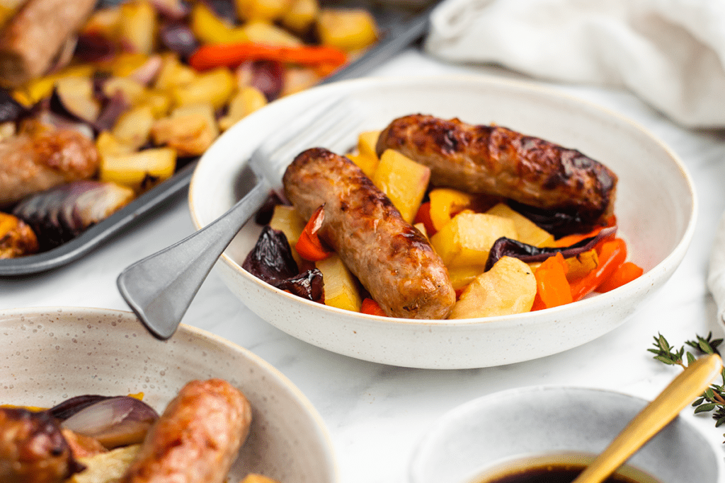 A serving of sausage and veg tray bake in a dish