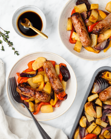 Top down view of two dishes of a roasted sausage and vegetable dinner