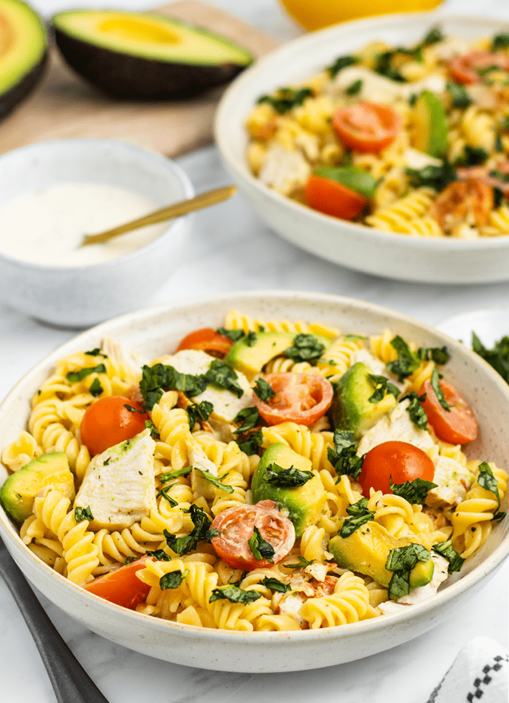 A bowl of creamy chicken, avocado and tomato pasta